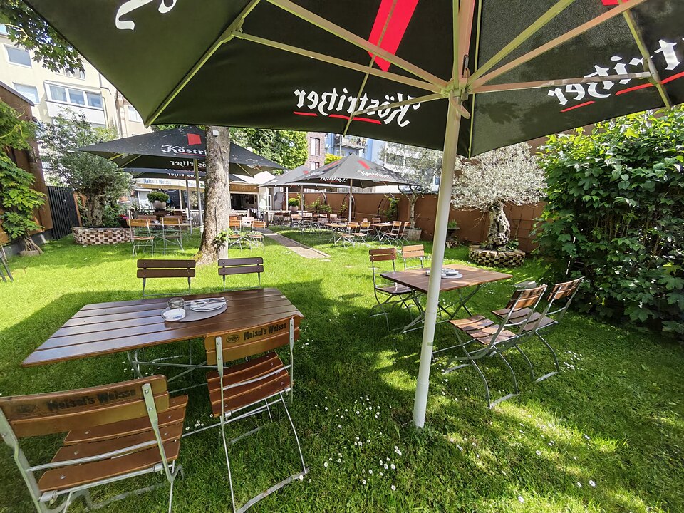 Tische unter Sonnenschirmen auf der grünen Gartenterrasse des Pelayo